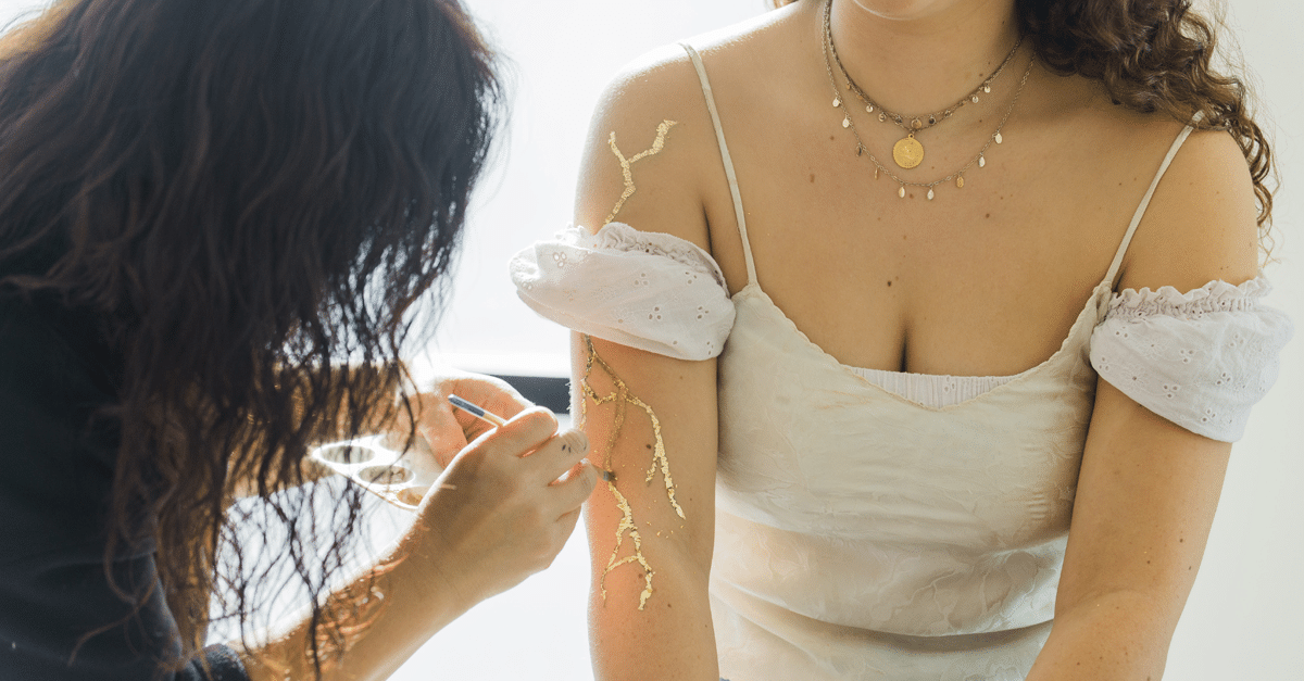 Arm being painted with kintsugi gold lines
