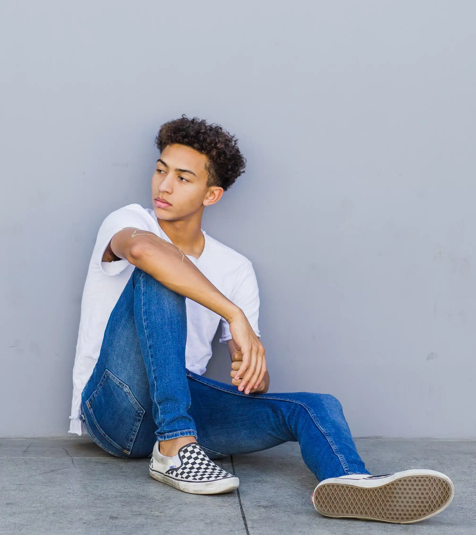 boy sitting on ground leaning against wall